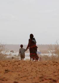 Eine Mutter und ihr Kind auf dem Weg durch eine ausgetrpcknete Landschaft in Äthiopien. Foto: Roberto Schmidt / AFP