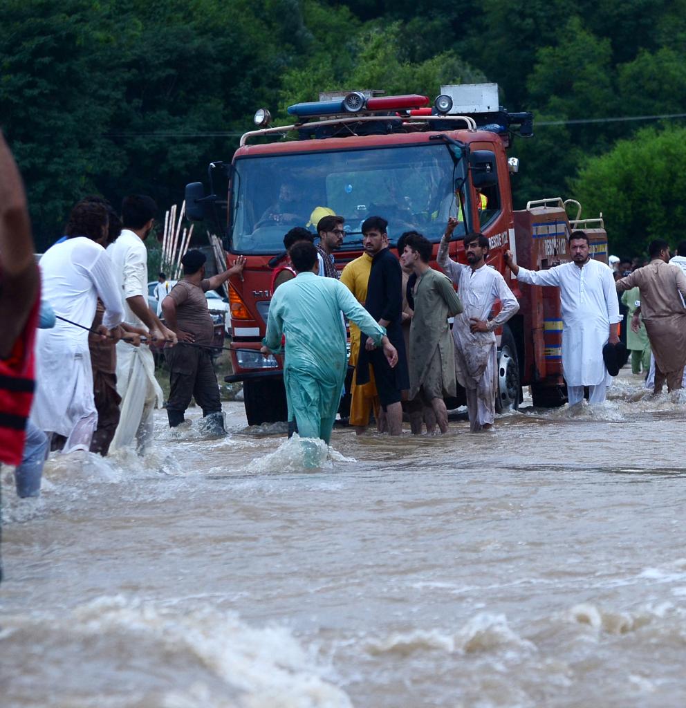 Betroffene der Flut in Pakistan versuchen ein Feuerwehrauto aus dem Wasser zu ziehen. Foto: Hussain Ali Anadolu / AFP 