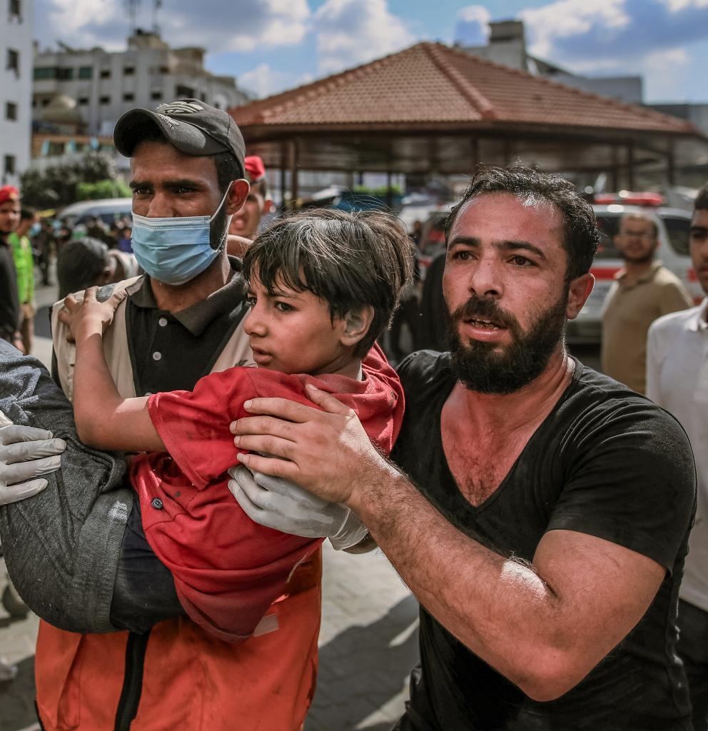 Zwei Männer tragen ein Kind nach einem Bombenangriff im Gazastreifen. Foto Mohammed Zaanoun/AFP