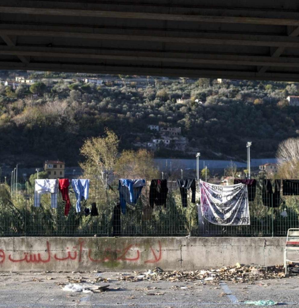 Geflüchtete Menschen haben ihre Kleidung auf einem Zaun aufgehängt. Foto: Michele Lapini