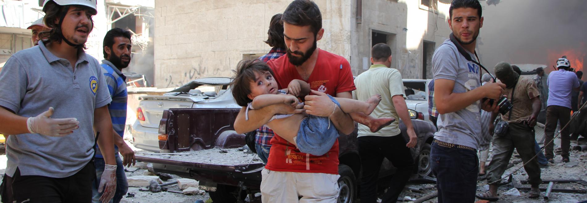 Ein Vater trägt sein verletztes Kind, Syrien. Foto: Omar Haj Kadour, AFP