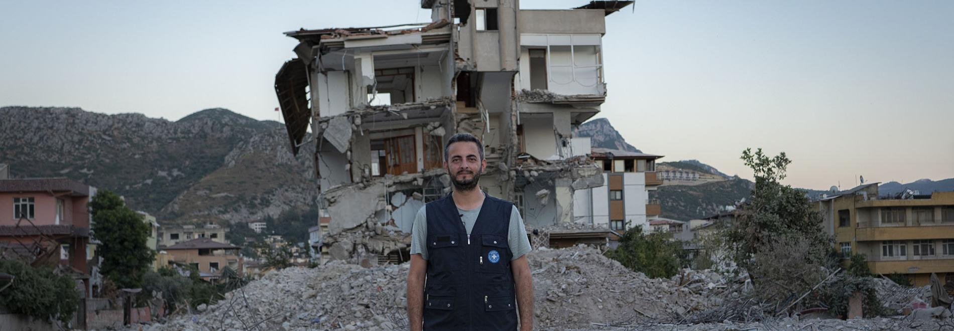 Ein Mitglied des Teams von Ärzte der Welt steht vor einem Gebäude, das bei dem Erdbeben in der Region Hatay in der Türkei zerstört wurde. Foto: Huseyin Aldemir