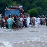 Betroffene der Flut in Pakistan versuchen ein Feuerwehrauto aus dem Wasser zu ziehen. Foto: Hussain Ali Anadolu / AFP 