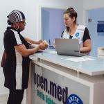 Eine Ärzte der Welt Mitarbeiterin gibt einer Patientin eine Visitenkarte in der open.med Praxis Berlin. Foto: Max Avdeev