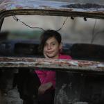 Ein junges Mädchen spielt in den Überresten eines Fahrzeugs, das durch die Kämpfe in Syrien zerstört wurde. Foto: Ärzte der Welt (DDD)