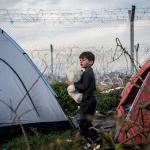 Kind zwischen Zelten am Grenzzaun zwischen Griechenland und Mazedonien (FYROM)