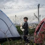 Kind zwischen Zelten am Grenzzaun zwischen Griechenland und Mazedonien (FYROM)