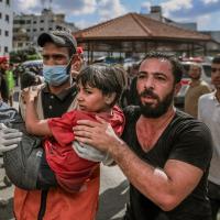 Zwei Männer tragen ein Kind nach einem Bombenangriff im Gazastreifen. Foto Mohammed Zaanoun/AFP