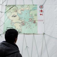  Ein Flüchtling betrachtet eine Landkarte, auf der die Insel Chios markiert ist.