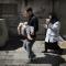 Ein Vater trägt sein Kind, das bei einem Bombenangriff verletzt wurde. Foto: Marco Longari, AFP