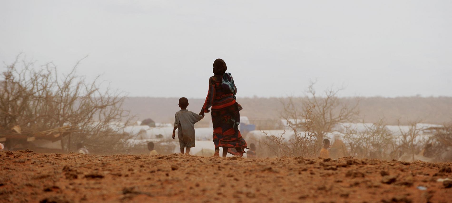 Eine Mutter und ihr Kind auf dem Weg durch eine ausgetrpcknete Landschaft in Äthiopien. Foto: Roberto Schmidt / AFP