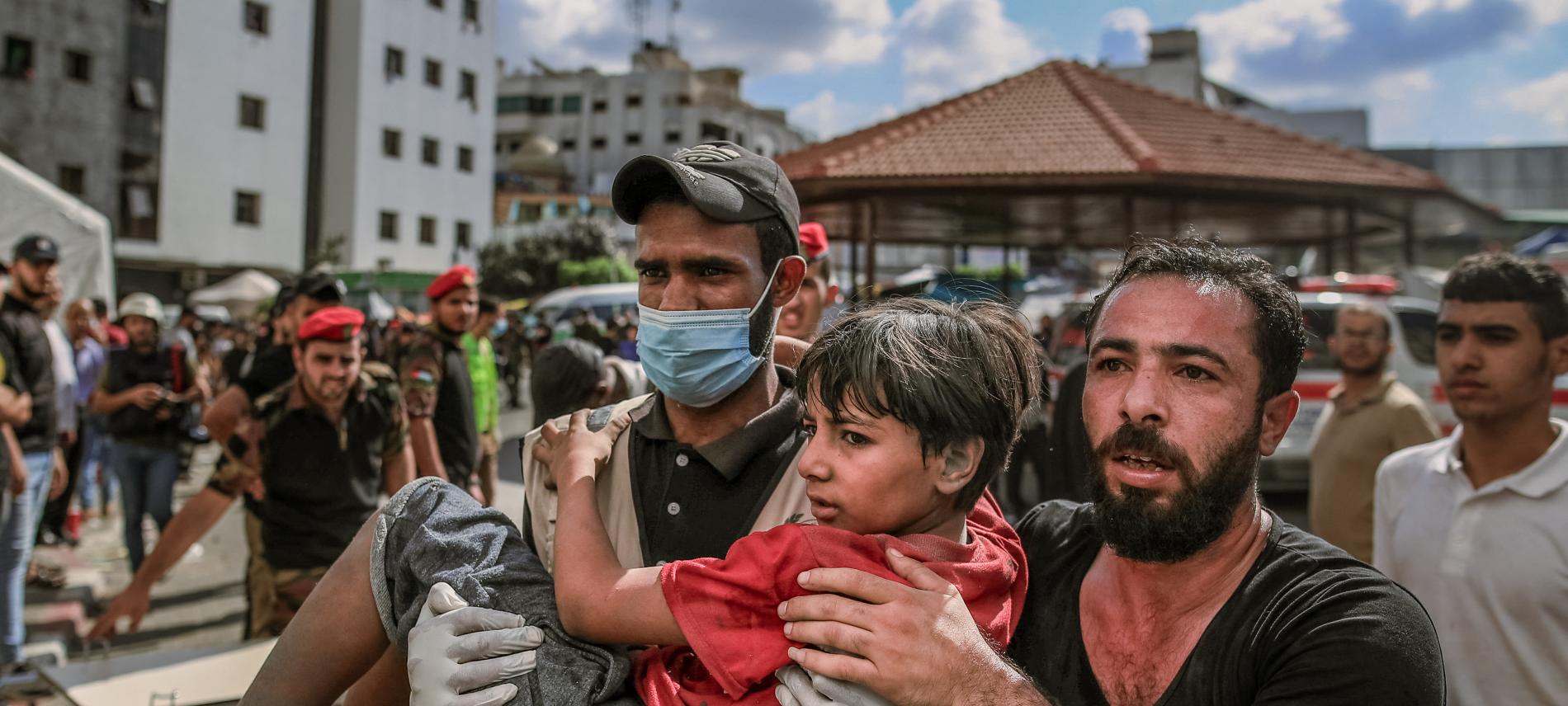 Zwei Männer tragen ein Kind nach einem Bombenangriff im Gazastreifen. Foto Mohammed Zaanoun/AFP