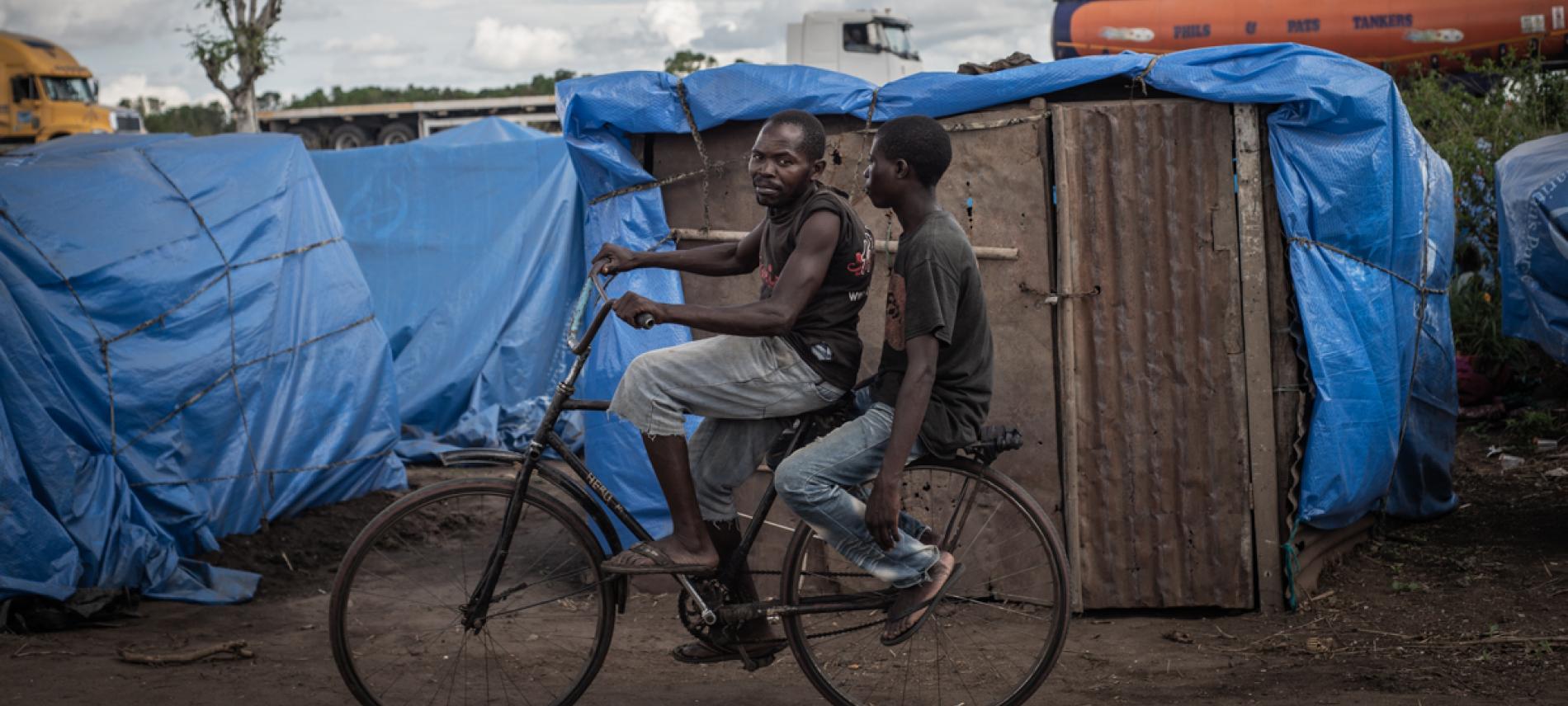 Männer fahren Rad in einem Flüchtlingslager in Mosambik 