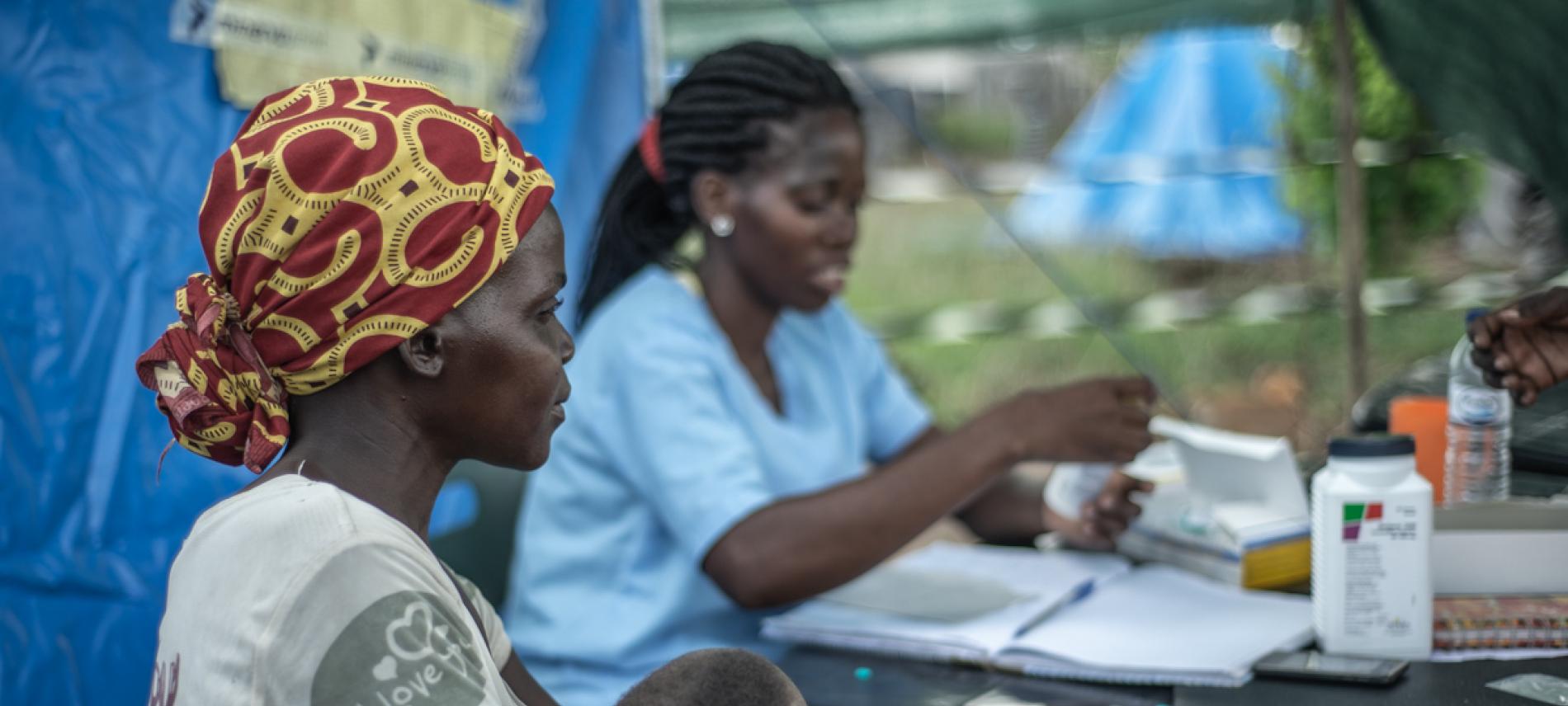 In einem provisorischen Zeltlager lässt eine Frau Ihr Kind von der pädiatrischen Fachkraft des Ärzte der Welt-Teams untersuchen. Mosambik. Foto: Czuko Williams