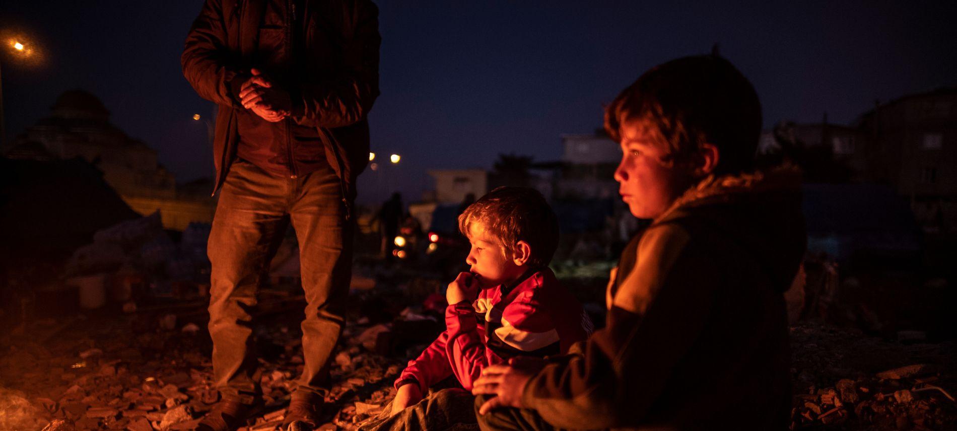 Kinder, deren Zuhause durch das Erdbeben 2023 an der türkisch-syrischen Grenze zerstört wurde, wärmen sich an einem Holzfeuer in einem provisorischen Lager. Foto: Olivier Papegnies