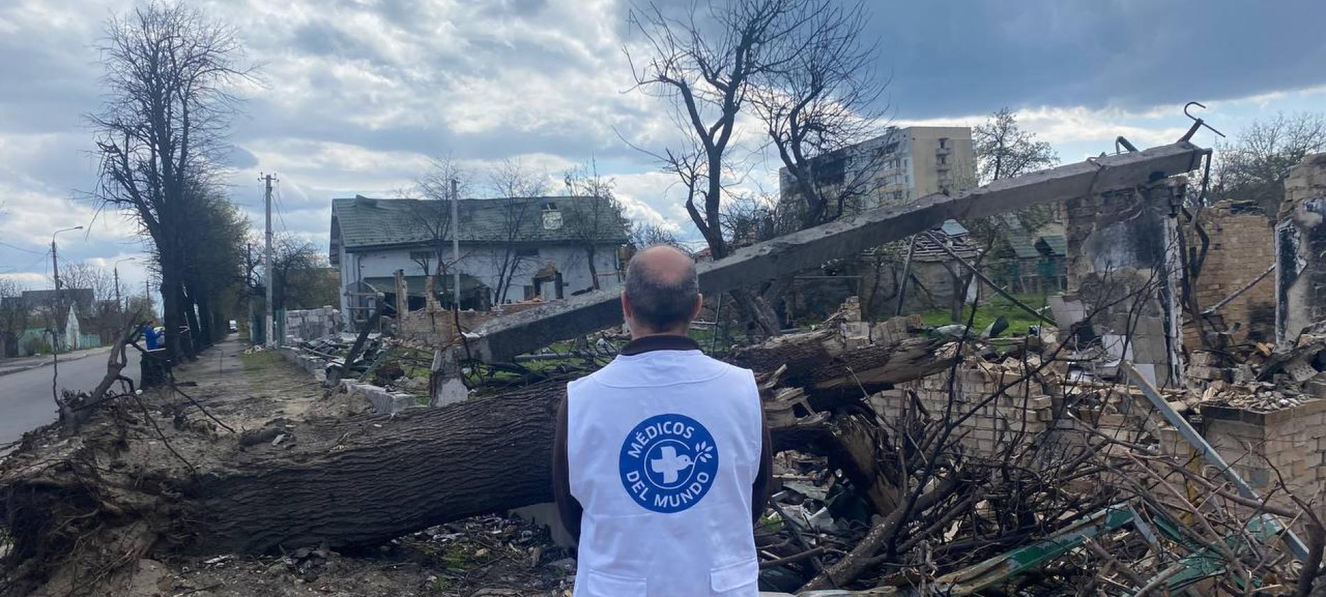 Ein Mitarbeiter von Ärzte der Welt in vor einem vom Krieg in der Ukraine zerstörten Gebäude. Ein Mitarbeiter von Ärzte der Welt in einem von Krieg in der Ukraine zerstörtem Gebiet.