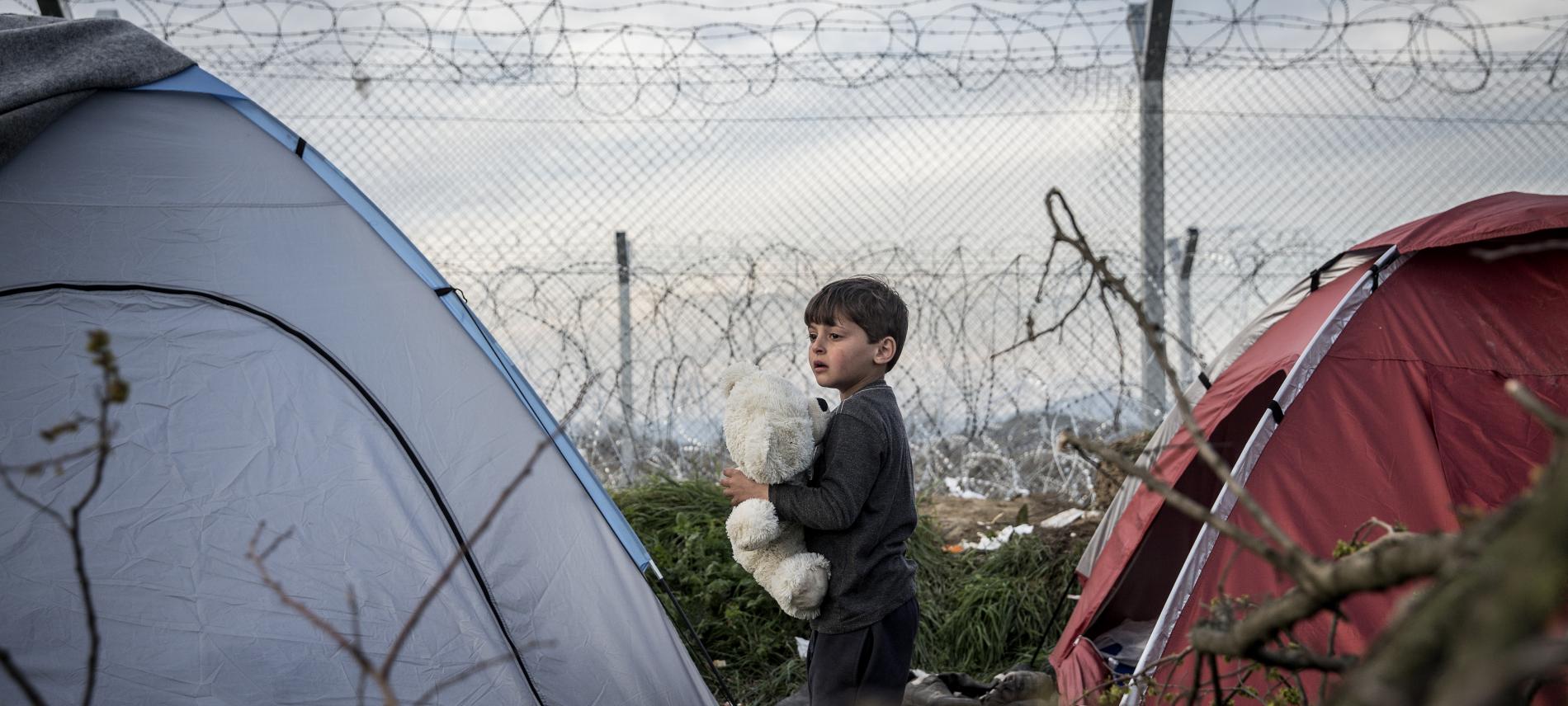 Kind zwischen Zelten am Grenzzaun zwischen Griechenland und Mazedonien (FYROM)