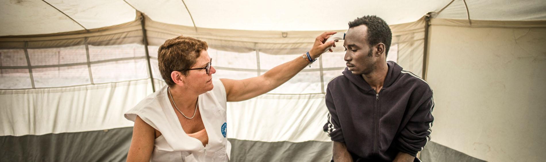 Eine ehrenamtliche Ärztin behandelt einen Migranten in Calais. Foto: Olivier Papegnies