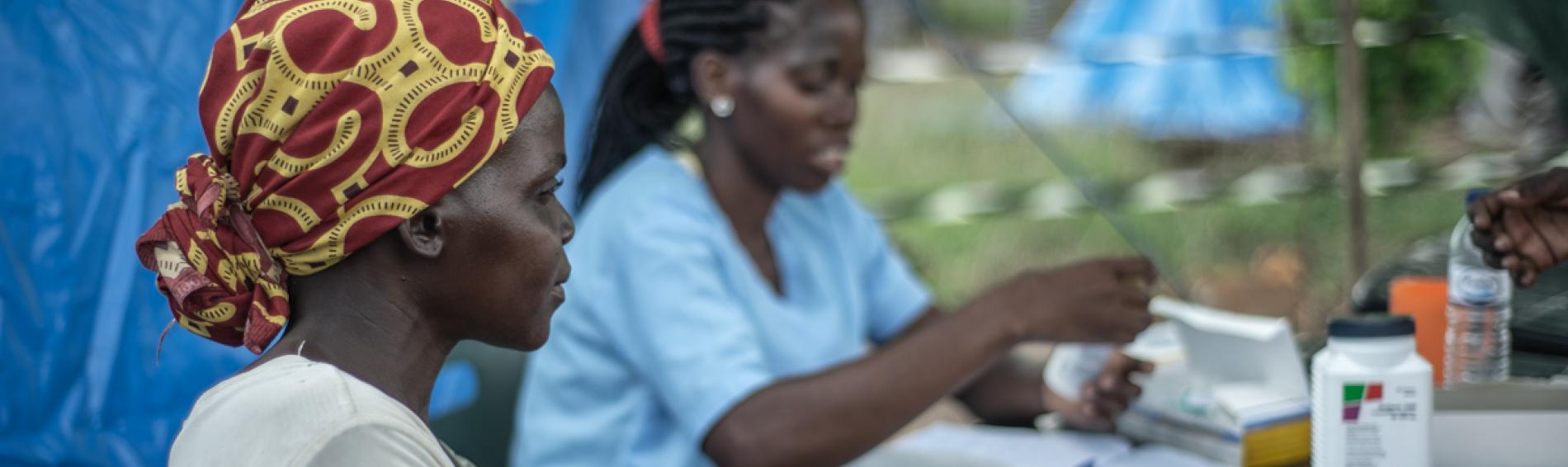 In einem provisorischen Zeltlager lässt eine Frau Ihr Kind von der pädiatrischen Fachkraft des Ärzte der Welt-Teams untersuchen. Mosambik. Foto: Czuko Williams