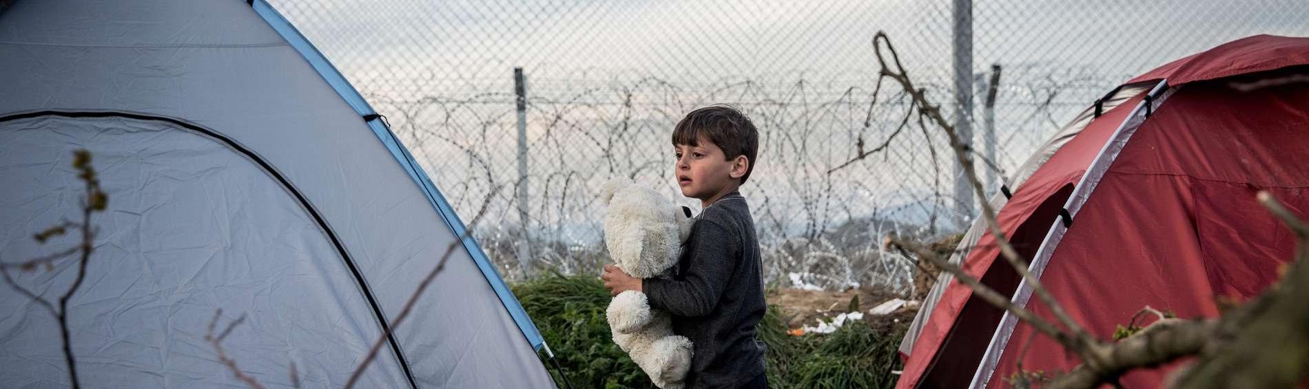 Kind zwischen Zelten am Grenzzaun zwischen Griechenland und Mazedonien (FYROM)