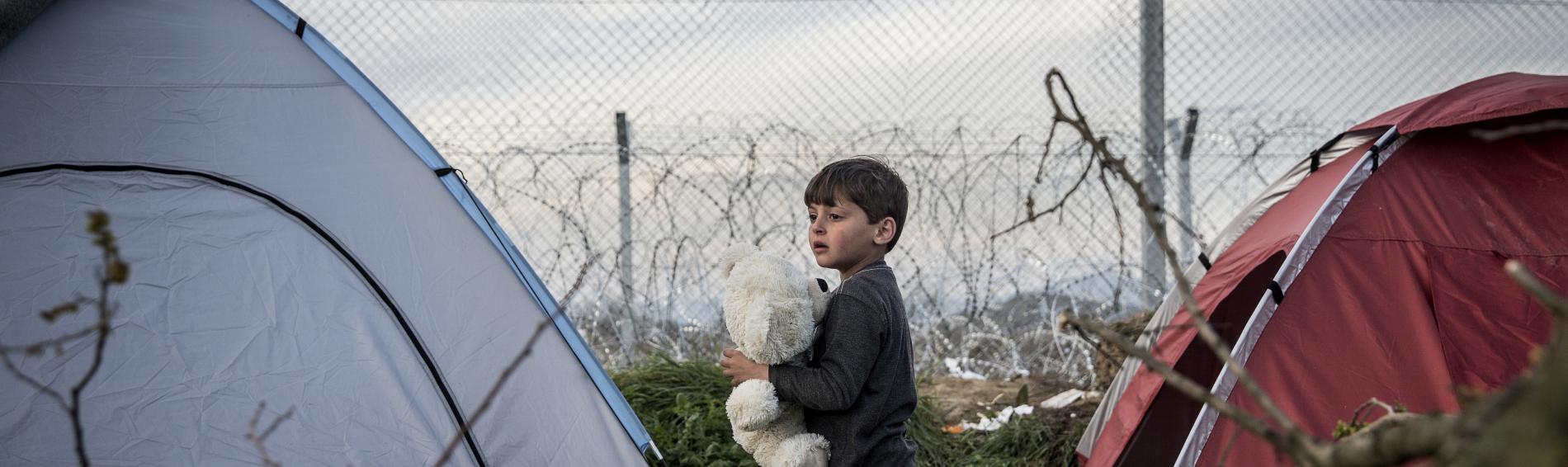 Kind zwischen Zelten am Grenzzaun zwischen Griechenland und Mazedonien (FYROM)