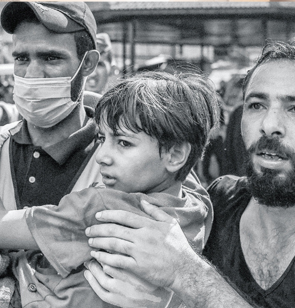 Zwei Männer helfen einem Kind in den Palästinensischen Gebieten. Foto: Mohammed Zaanoun