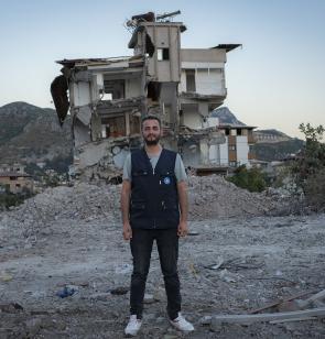Ein Mitglied des Teams von Ärzte der Welt steht vor einem Gebäude, das bei dem Erdbeben in der Region Hatay in der Türkei zerstört wurde. Foto: Huseyin Aldemir