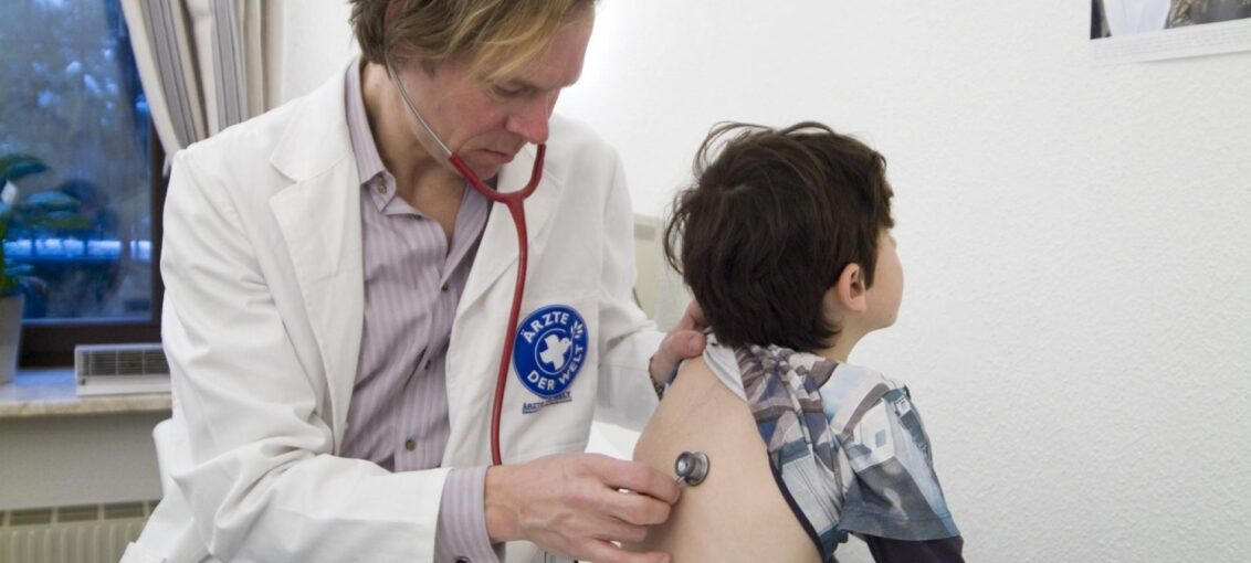 Ein Arzt von Ärzte der Welt hört ein Kind mit einem Stethoskop ab. Ein Arzt von Ärzte der Welt hört ein Kind mit einem Stethoskop ab.