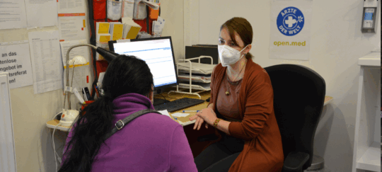 Eine Patientin sitzt in der open.med Praxis in München einer Ärztin gegenüber.