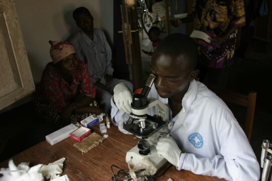 Ein Mitarbeiter von Ärzte der Welt schaut in ein Mikroskop in einer medizinischen Einrichtung in der DR Kongo. © Bruno Fert