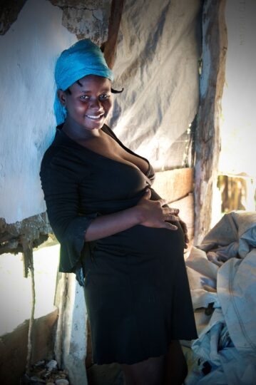 Eine schwangere Haitianerin hat ihre Hände über den Bauch gelegt und lächelt in die Kamera. © Pierre W. Henry