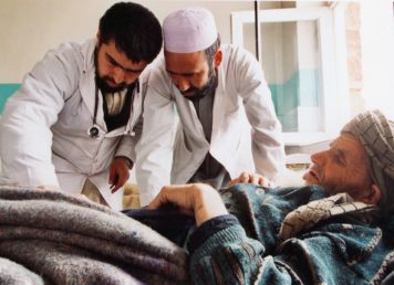 zwei Ärzte in Afghanistan beugen sich über einen Patienten der vor ihnen liegt