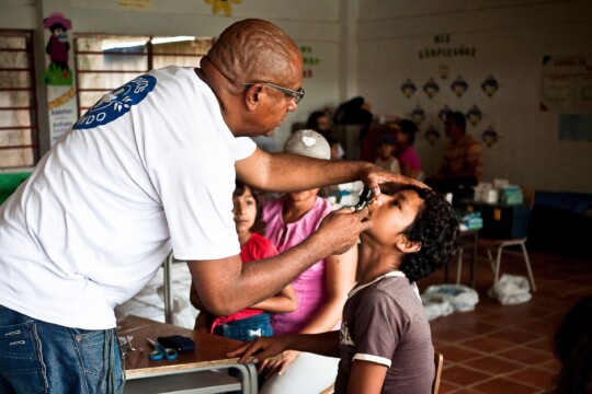 Kolumbien: Ein Arzt untersucht einen Jungen, im Hintergrund sitzt eine Frau mit einem weiteren Kind. Ärzte der Welt leistet medizinische Hilfe in Kolumbien. ©Andia Berg