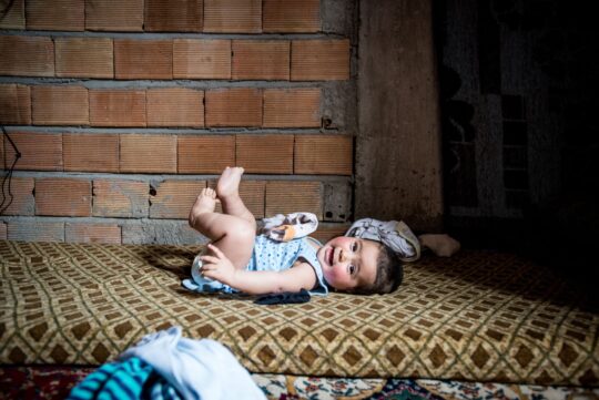 Ein kleines Baby liegt lachend auf einer Matratze auf dem Boden und hat die Füße in die Luft gestreckt. Ärzte der Welt leistet in der Türkei unter anderem medizinische Versorgungen rund ums Thema Schwangerschaft und Geburt. © Guillaume Pinon