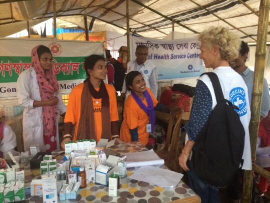 Bangladesch: Mehrere Mitarbeiter von Ärzte der Welt stehen lächelnd in einem Gesundheitszentrum um einen Tisch mit Medikamenten herum. © Lea Gibert