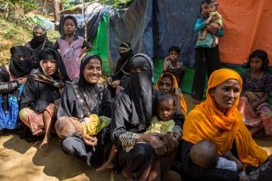 Bangladesch: Mehrere Frauen mit kleinen Kindern sitzen hintereinander auf dem Boden. Sie haben ihre Kinder jeweils auf dem Schoß. © Ärzte der Welt