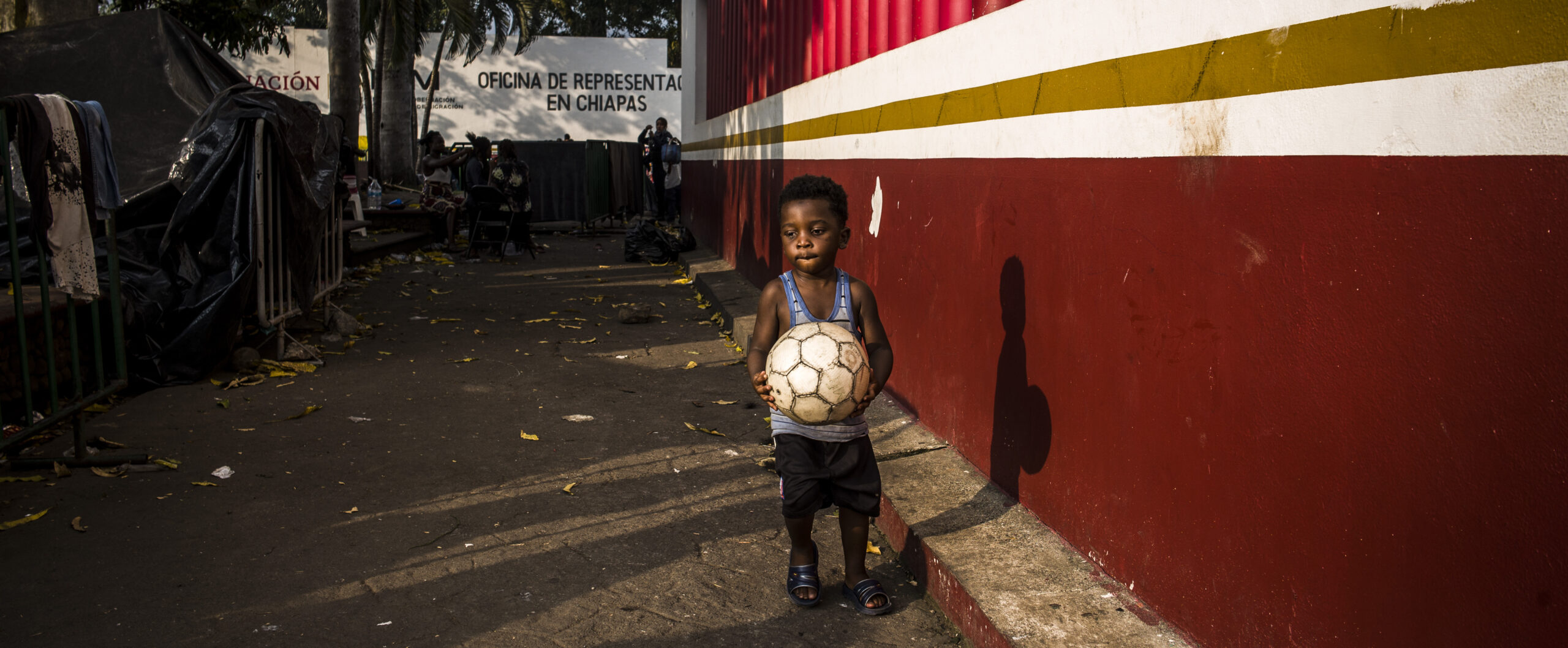 Mexiko: Ein Junge läuft mit einem Fußball in der Hand eine Mauer entlang. © Olivier Papegnies