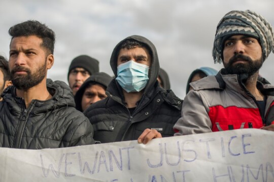 Bosnien: Mehrere Männer demonstrieren für Gerechtigkeit. Sie halten ein Schild und schauen in die Ferne. © Michele Lapini/Valerio Muscella