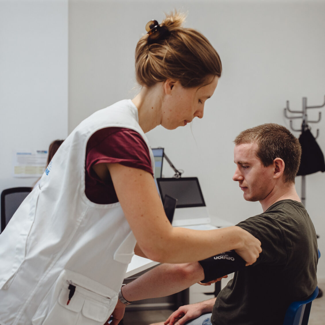 In der medizinischen Anlaufstelle von open.med Berlin-Lichtenberg bringt eine Ärztin ein Blutdruckmessgerät am Arm eines Patienten an.