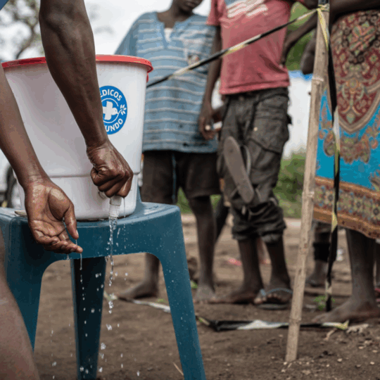 Ein Mosambikaner wäscht sich die Hände an einem Wasserfass von Ärzte der Welt. © Czuko Williams