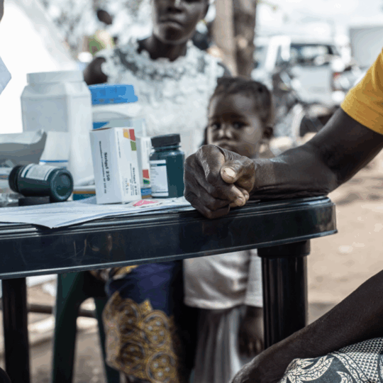 Ein Mann sitzt an einem Tisch, vor ihm liegen Medikamente. © Czuko Williams