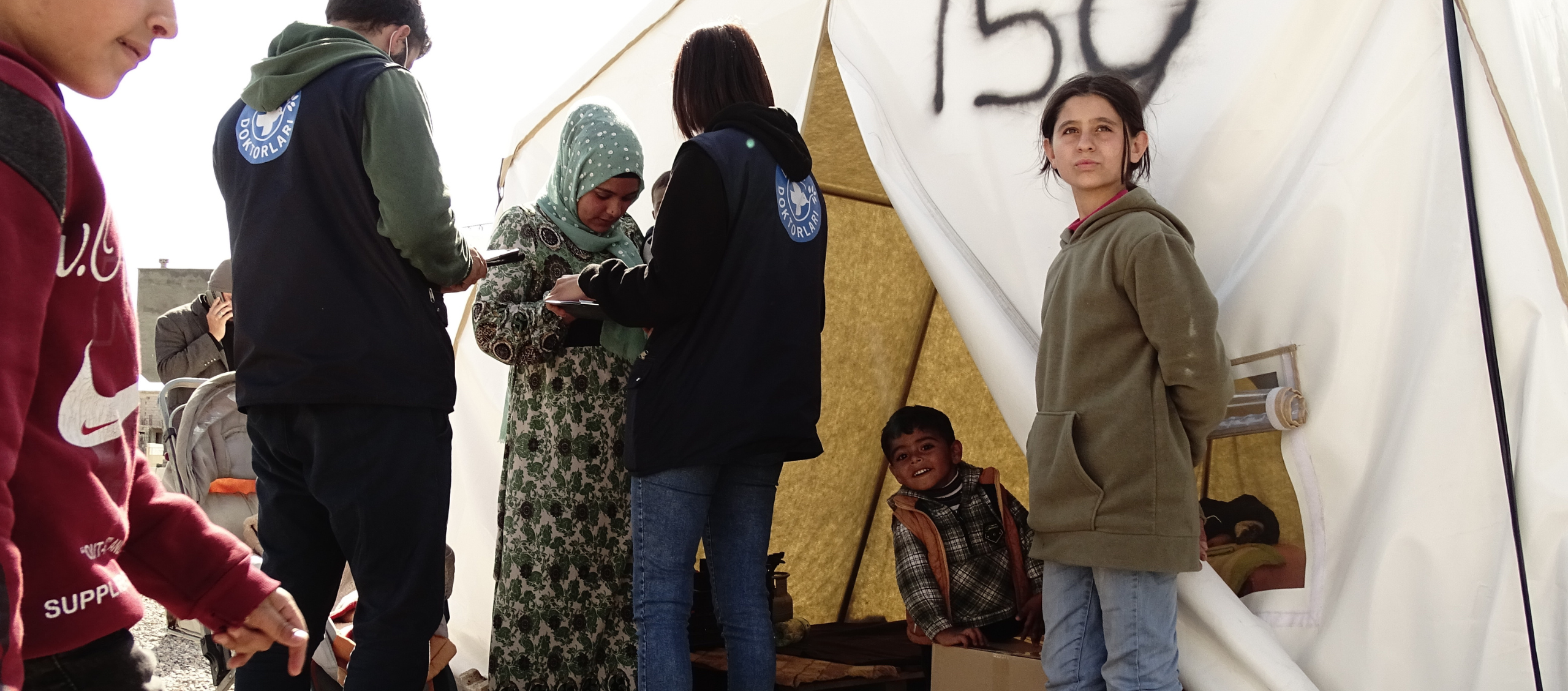 Unsere Mitarbeitenden sprechen mit einer Familie in der Zeltstädte für Geflüchtete in Hatay. © Ärzte der Welt