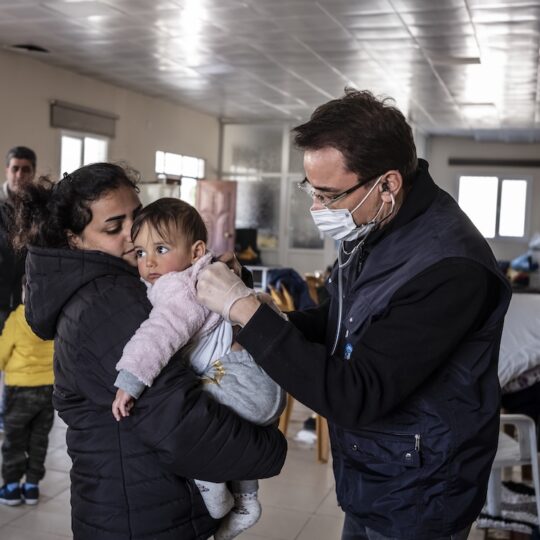 Türkei: Nach dem großen Erdbeben 2023 hört ein Mitarbeiter von Ärzte der Welt ein kleines Kind mit einem Stethoskop ab.