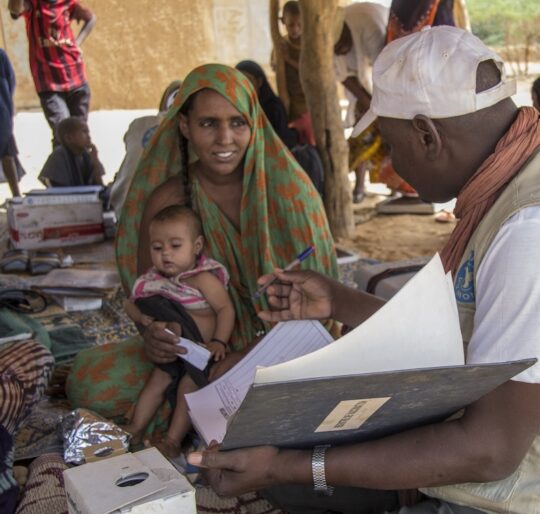 Mali: Ein Mitarbeiter von Ärzte der Welt spricht mit einer Mutter, die ihr Kleinkind im Arm hält.