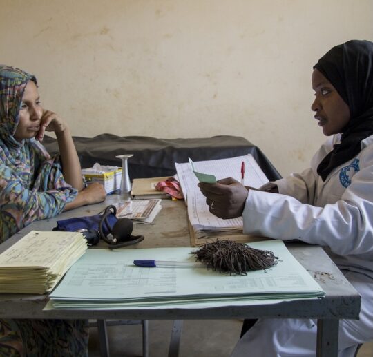 Mali: Eine Mitarbeiterin von Ärzte der Welt und eine Patientin sitzen sich am Tisch gegenüber und sprechen miteinander.