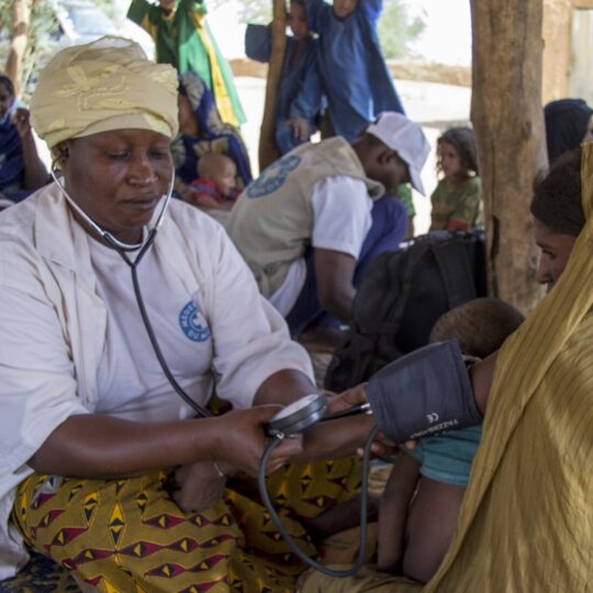Ein Mitarbeiter von Ärzte der Welt misst einer Patientin in Mali den Blutdruck.