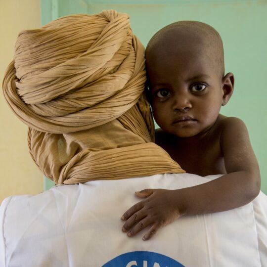 Mali: Ein Mitarbeiter von Ärzte der Welt hält ein Kleinkind, das in die Kamera guckt.