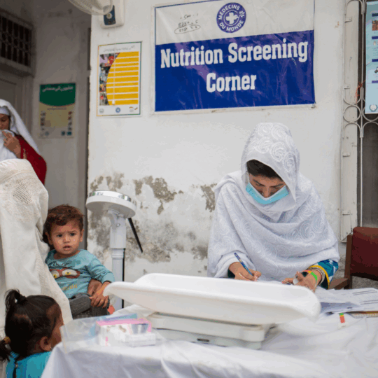 Eine Ärztin von Ärzte der Welt untersucht zwei Kinder auf Mangelernährung. Die Mutter sitzt mit ihren Kindern vor der Ärztin. ©Saiyna Bashir