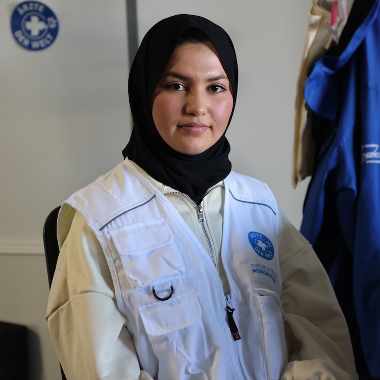Junge Frau, die Hijab und Weste mit Logo von Ärzte der Welt trägt. 