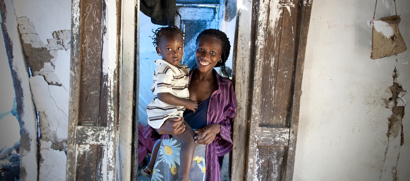 Eine Frau steht in einem Türeingang, auf ihrem Arm ein Kleinkind. Ärzte der Welt leistet medizinische Hilfe in Haiti.